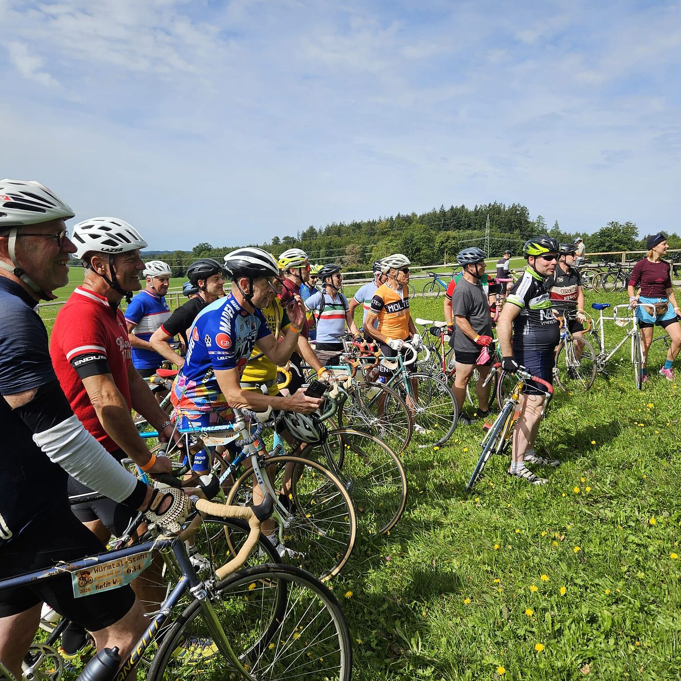 Gruppe von Tourenteilnehmenden mit ihren Oldtimer Rennräder auf Wiese