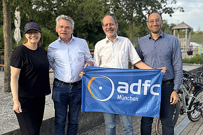 Eine Frau und drei Männer mit ADFC München Fahne neben Fahrrädern