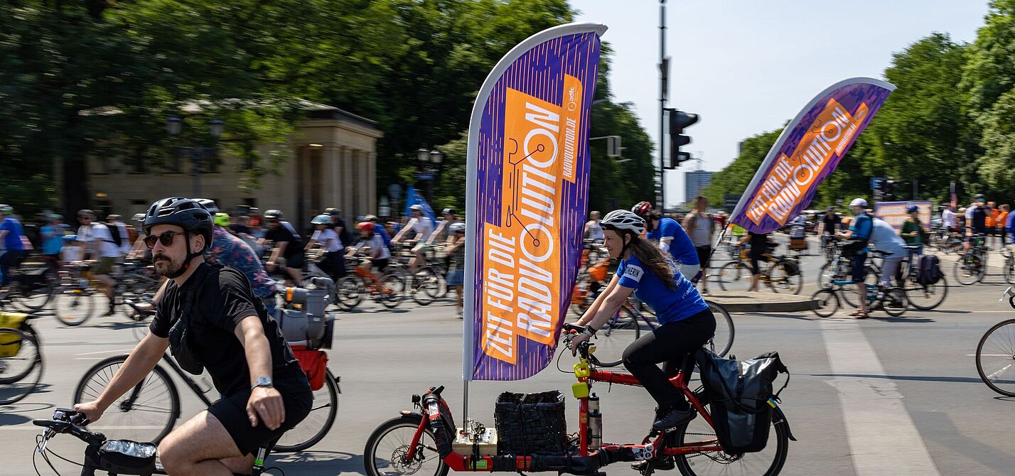 ADFC-Sternfahrt Berlin 2023 Viele Menschen auf Fahrrädern. An einem Rad befindet sich eine große Fahne mit dem Wort "Radvolution" darauf.